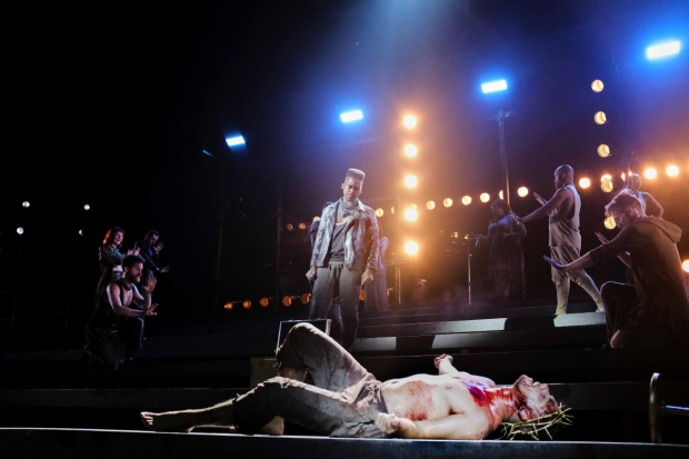 A scene from Jesus Christ Superstar. Jesus, bloodied, lies on the floor as Judas looks down at him.