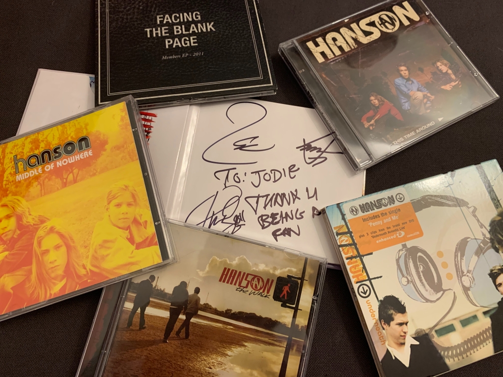 Various Hanson albums placed next to each other at random, with one in the middle open to a signed page that says "thanks for being a fan"
