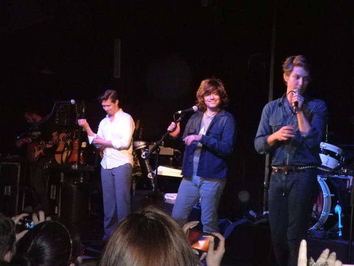Hanson standing behind microphones onstage