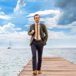 Neville Parker (Ralf Little) looks perplexed as he walks along a jetty towards the camera, with a big blue sky behind him.